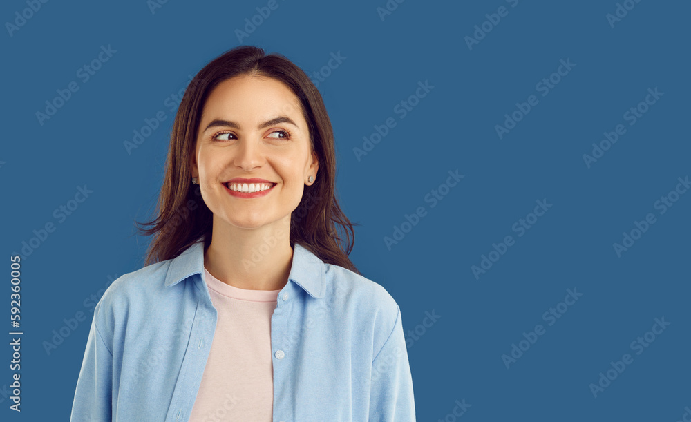 Happy cheerful joyful beautiful young Caucasian woman in casual shirt standing isolated on dark blue background, looking at copy space side, thinking about something pleasant or funny and smiling Happy cheerful joyful beautiful young Caucasian woman in casual shirt standing isolated on dark blue background, looking at copy space side, thinking about something pleasant or funny and smiling