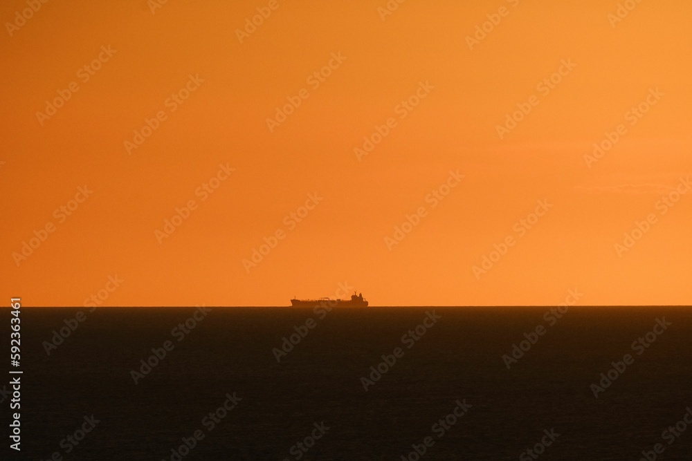 Beautiful view of a ship in the sea during orange sunset