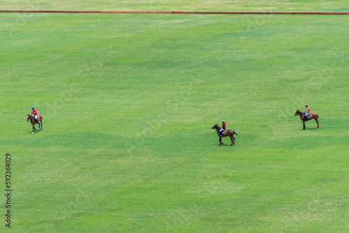 Three polo players on their horses play in a field on the outskirts of Lima, Peru