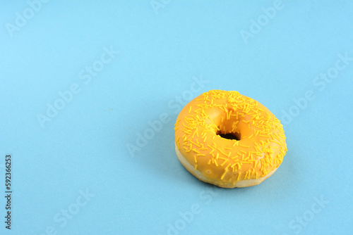 A yellow donut with yellow icing on a blue background, copy space