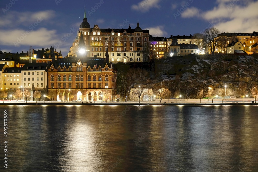 Beautiful scenery of illuminated Stockholm waterfront view towards Sodermalm district with historic Mariahissen building and Monteliusvagen, Sweden