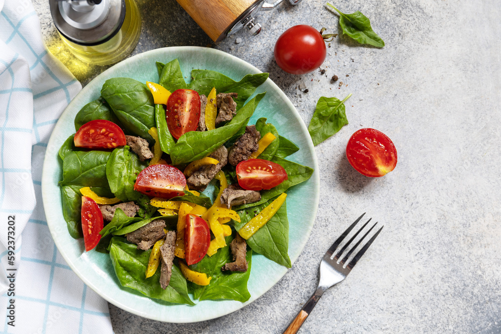 Warm salad of young spinach, chicken liver, tomatoes and grilled peppers with spices and balsamic. Healthy keto diet low carb. View from above. Copy space. Warm salad of young spinach, chicken liver, tomatoes and grilled peppers with spices and balsamic. Healthy keto diet low carb. View from above. Copy space.