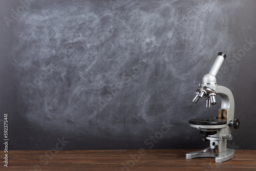 Back to school - microscope on the desk, Education concept. Blackboard background