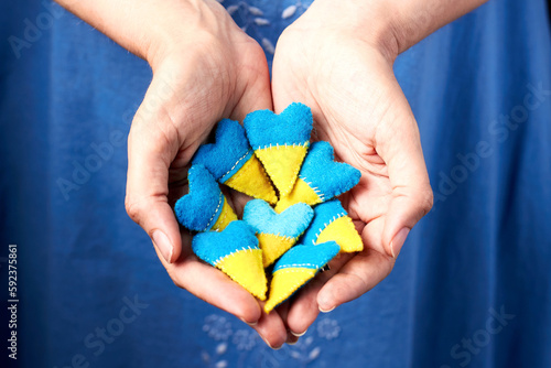 Wallpaper Mural Ukraine flag theme. Many heart shape pin badge made of blue and yellow stuffed felt in woman hand. Topical issues of war. Freedom fighters. Support of nations, unity Torontodigital.ca