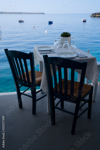 relaxing chairs and dinner table with view of caldera, Santorini, Greece © neirfy