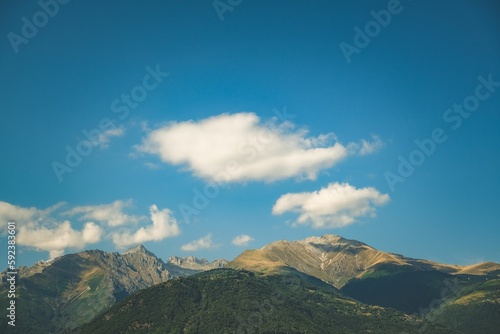 Low-angle shot of green mountains with the sky in the background and sunlight on