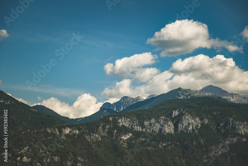Shot of rocky and green mountains with the sky and clouds in the background and sunlight on