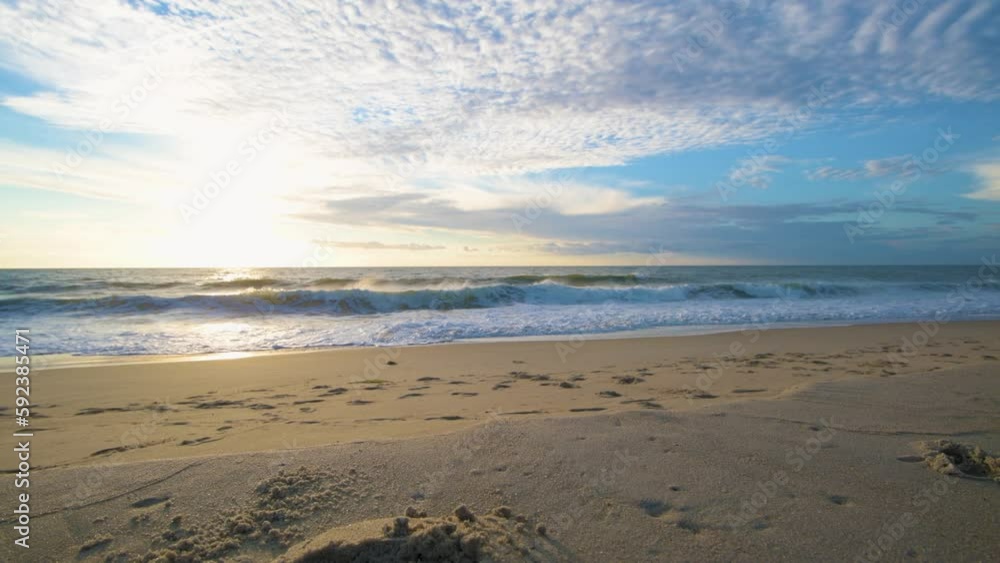 Low-angle shot of sea waves flooding the sandy sunlit Bethany beach at sunset skyline background Low-angle shot of sea waves flooding the sandy sunlit Bethany beach at sunset skyline background