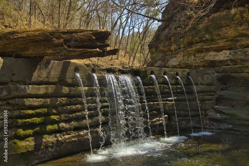 A small stream forms a waterfall as it is channeled through holes in a retaining wall at Matthiessen State Park in Northern Illinois.