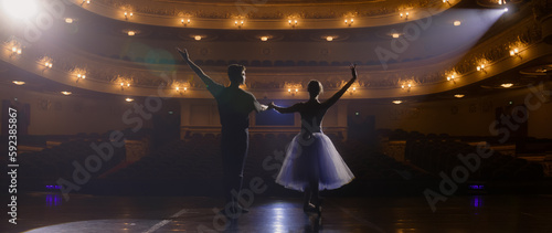 Fotografie Ballet dancers bow at the end of choreography rehearsal on classic theater stage illuminated by spotlight