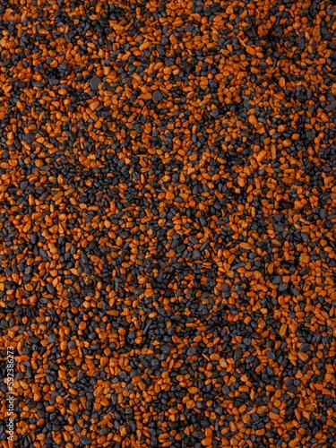 Vertical shot of small black and orange grains of sand for backgrounds