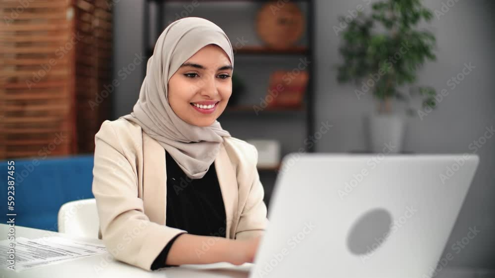 Smiling Turkish woman working laptop chatting online browsing internet e learning distance education Smiling Turkish woman working laptop chatting online browsing internet e learning distance education