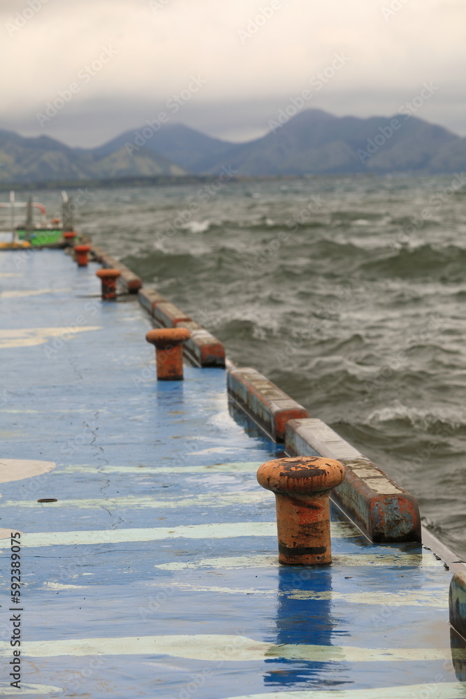 Fototapeta premium orange Rusty bollard on blue pier at inawashiro lake, Japan.