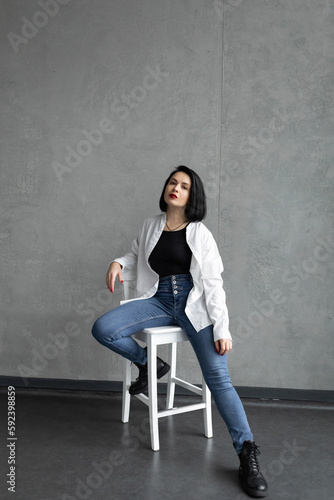 A woman in a white shirt sits on a chair