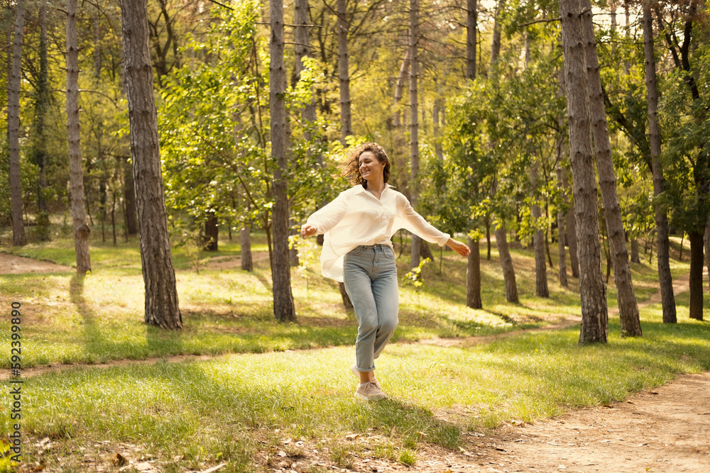Ecstatic young woman is dancing in the sunny green forest enjoying freedom in spring. Ecstatic young woman is dancing in the sunny green forest enjoying freedom in spring.