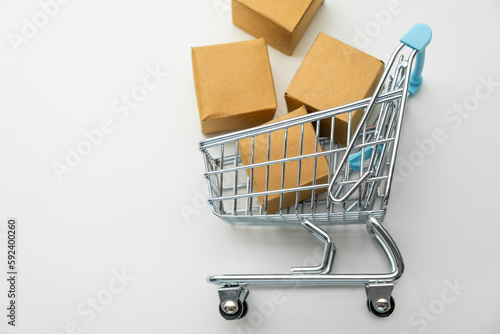 Top view of toy shopping cart with cardboard boxes on the white background with copy space. 
