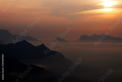 sun rises between the misty mountains and clouds