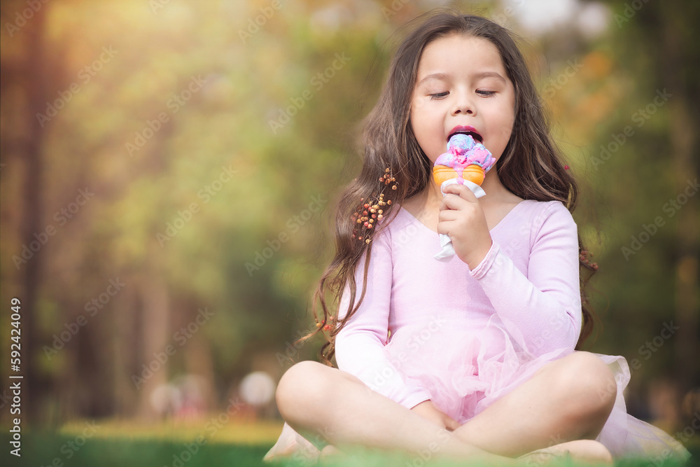 Cute blonde curly-haired girl eating a nice ice cream in the park, concept of children's day, copy space Cute blonde curly-haired girl eating a nice ice cream in the park, concept of children's day, copy space