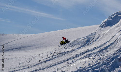 A man is riding snowmobile in mountains. Beautiful day in Swedish Lapland.
