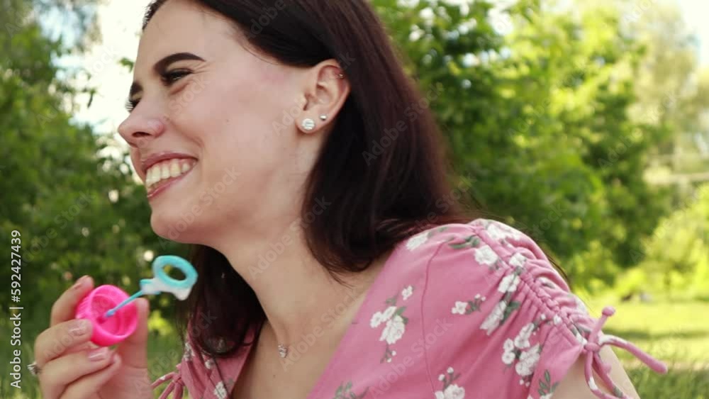 Woman sitting on white bedsheet, blowing soap bubbles, smiling. Lady have a rest in the city park, green grass lawn. Travel, vacation, picnic set
Woman sitting on white bedsheet, blowing soap bubbles, smiling. Lady have a rest in the city park, green grass lawn. Travel, vacation, picnic set