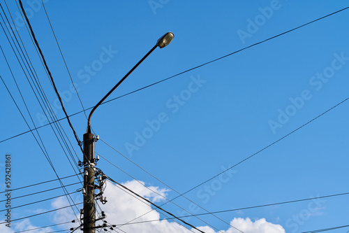 A street lamppost and many cables on a background of a blue sky with white clouds