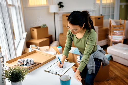 Asian woman going through checklist while before moving out of her apartment.