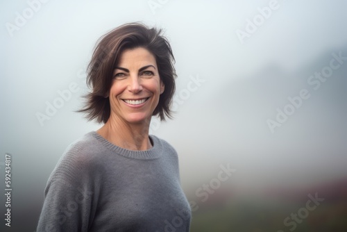 Portrait of a beautiful middle aged woman smiling in the fog.