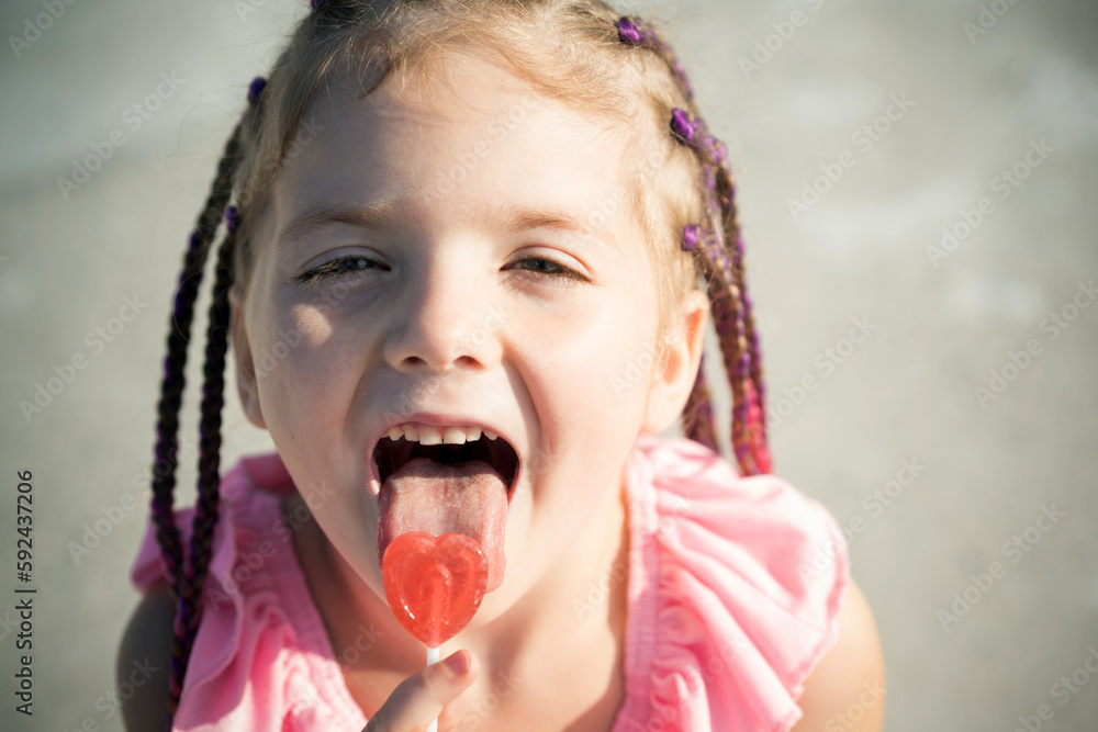 Little girl lick lollipop. Lifestyle portrait of cute kid outdoors ...