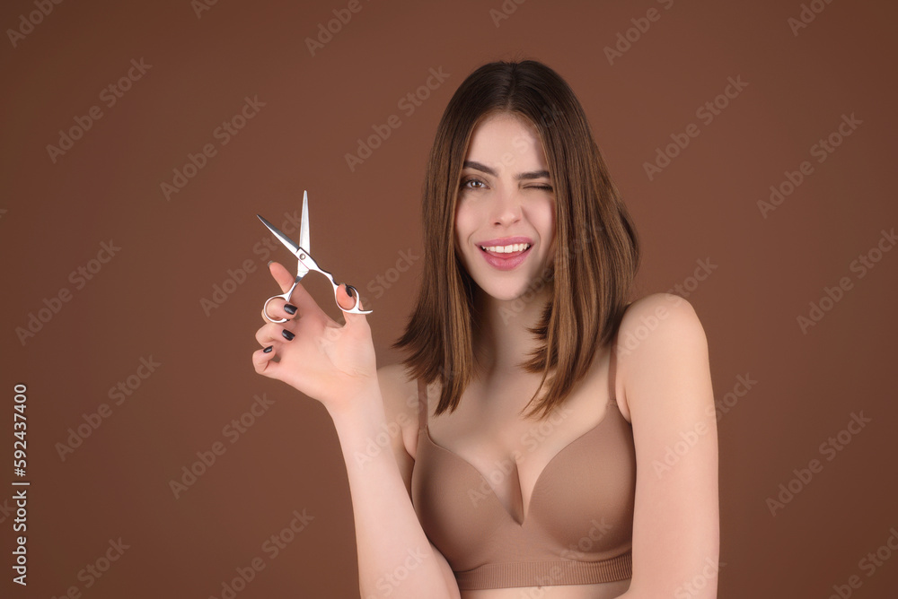 Fototapeta premium Haircut. Portrait of young woman hairdresser cutting hair with scissors. Girl with beautiful hair look at scissors. Hairs cut hairstyle with bangs. Hair care. Girl with straight hair holds scissors.