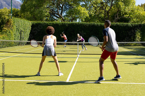 Happy diverse group of friends playing tennis at tennis court