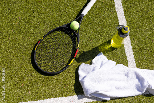 Close up of tennis ball, racket, towel and water bottle at tennis court