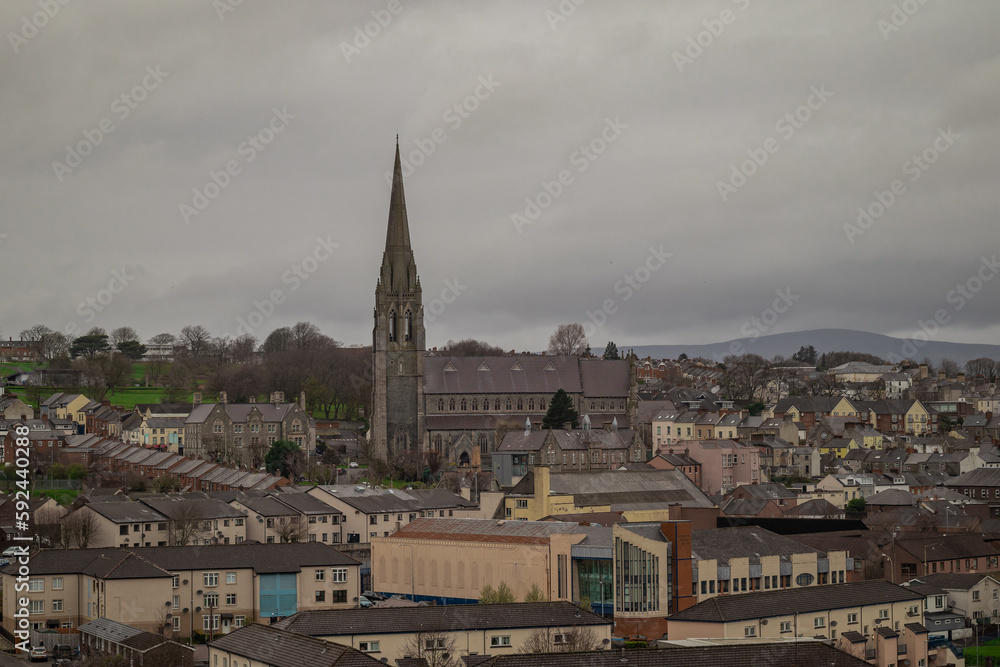 Panorama of Derry or Londonderry on a cloudy day viewed from the city walls. Green panorama of the city, church or cathedral visible.