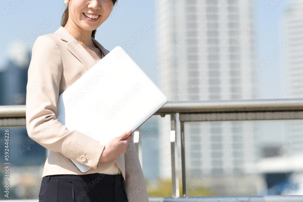屋外でPCを持つビジネスウーマン