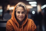 Portrait of beautiful mature woman in orange hoodie looking at camera.
