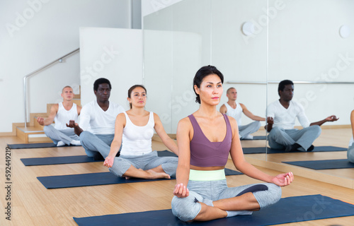 Man and woman making yoga meditation in lotus pose in fitness center