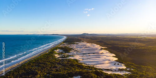 Aerial view of massive large sand dunes and Pacific ocean at sunset. Hat Head National Park, NSW, Australia