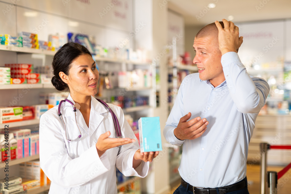 Woman pharmacist advises man medicine for headache pain. Help in choosing a medicine in a pharmacy