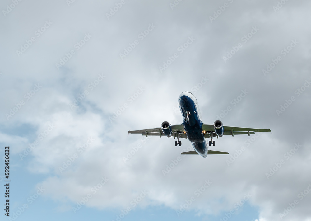 Background with a flying plane in the sky. Aircraft with landing gear in the sky. Travel concept with copy space