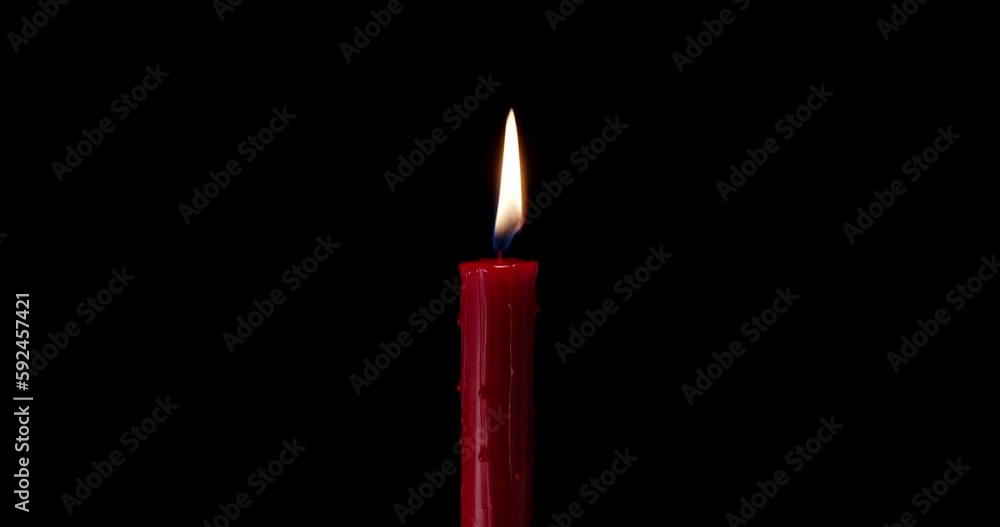 A single red candle burning. Isolated candle burning with dark background. Red paraffin candle with yellow shades burns on a black background. slow motion A single red candle burning. Isolated candle burning with dark background. Red paraffin candle with yellow shades burns on a black background. slow motion