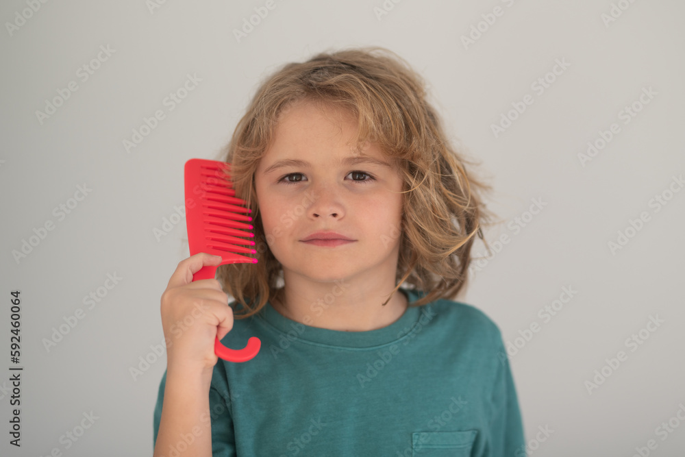 Child combing hair after shower. Child with tangled blonde long hair tries to comb it. Hair portrait kid with a comb. Child combing hair after shower. Child with tangled blonde long hair tries to comb it. Hair portrait kid with a comb.