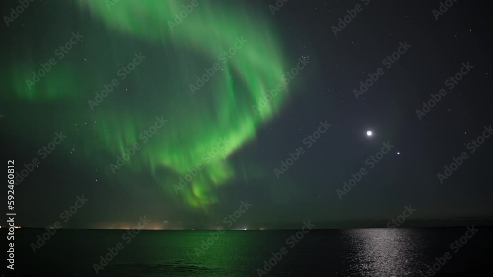 Bright Aurora borealis reflecting in ocean in front of Moon and Venus Bright Aurora borealis reflecting in ocean in front of Moon and Venus
