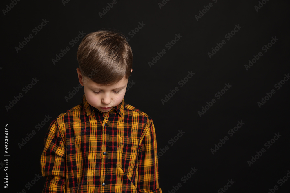 Upset boy on black background, space for text. Children's bullying Upset boy on black background, space for text. Children's bullying