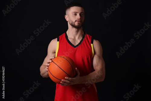Athletic young man with basketball ball on black background © New Africa