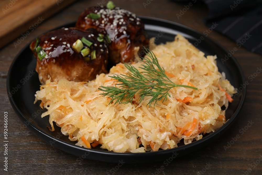 Plate with sauerkraut and chicken on wooden table, closeup