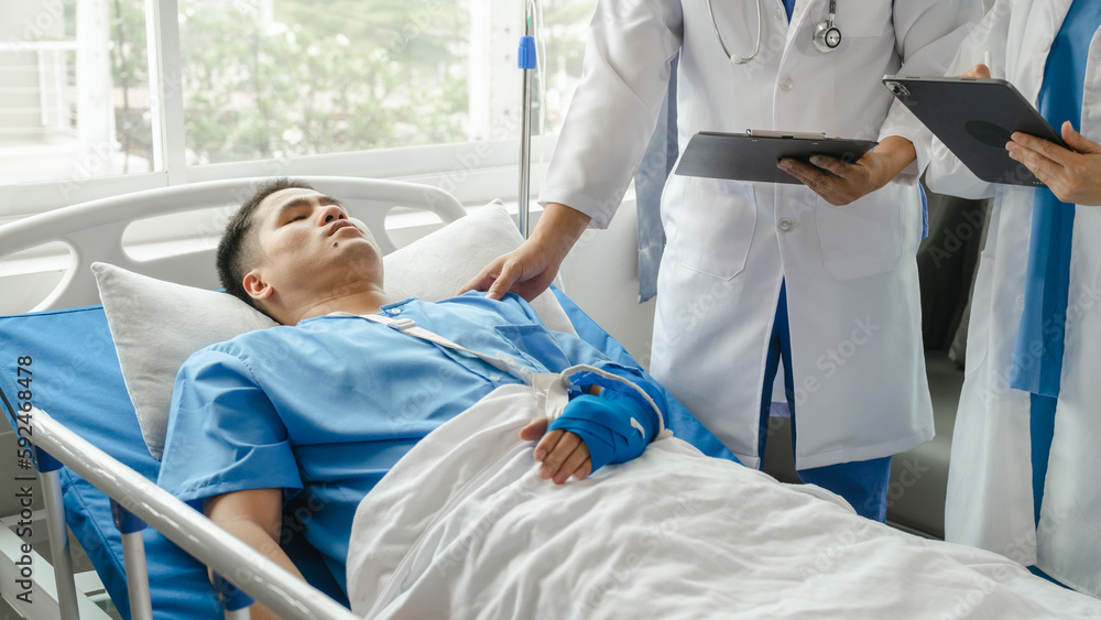 The medical team visits the car accident patients who are lying on the nursing bed and arm cast with wrapping nurse bandages splint to the arm. The medical team visits the car accident patients who are lying on the nursing bed and arm cast with wrapping nurse bandages splint to the arm.