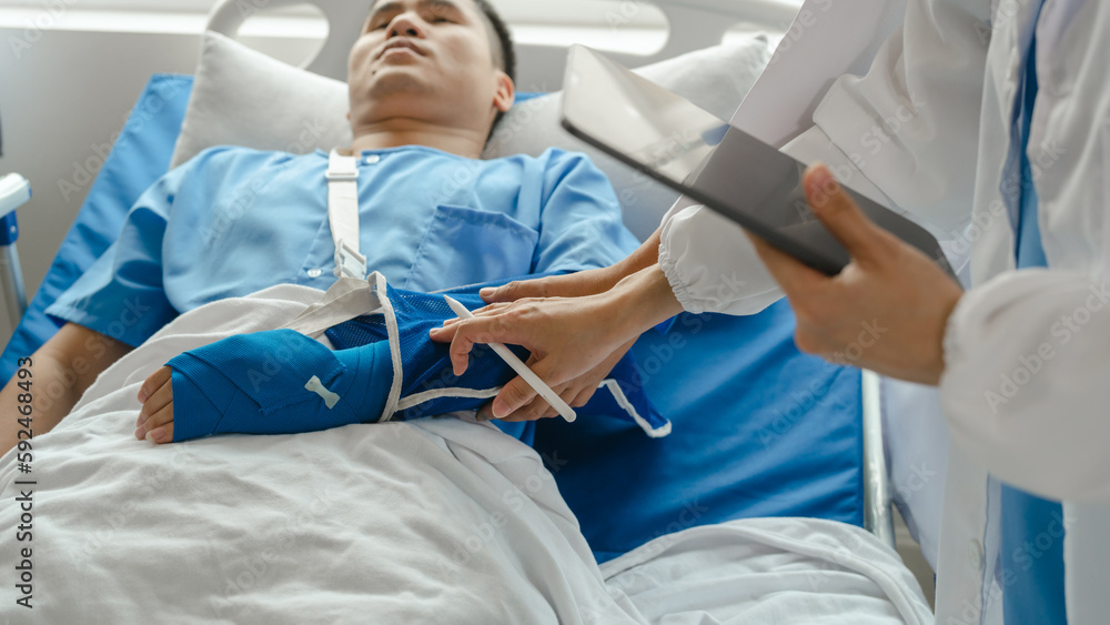 The medical team visits the car accident patients who are lying on the nursing bed and arm cast with wrapping nurse bandages splint to the arm. The medical team visits the car accident patients who are lying on the nursing bed and arm cast with wrapping nurse bandages splint to the arm.