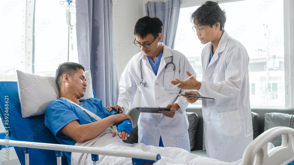 Obraz premium The medical team visits the car accident patients who are lying on the nursing bed and arm cast with wrapping nurse bandages splint to the arm.