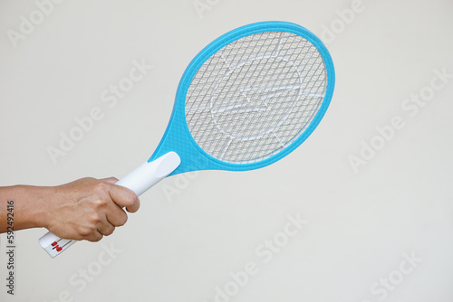 Closeup hand holds mosquito electric swatter racket. Concept, electric device to kill mosquitoes, insects, bugs by swatting to flying insects.          photo