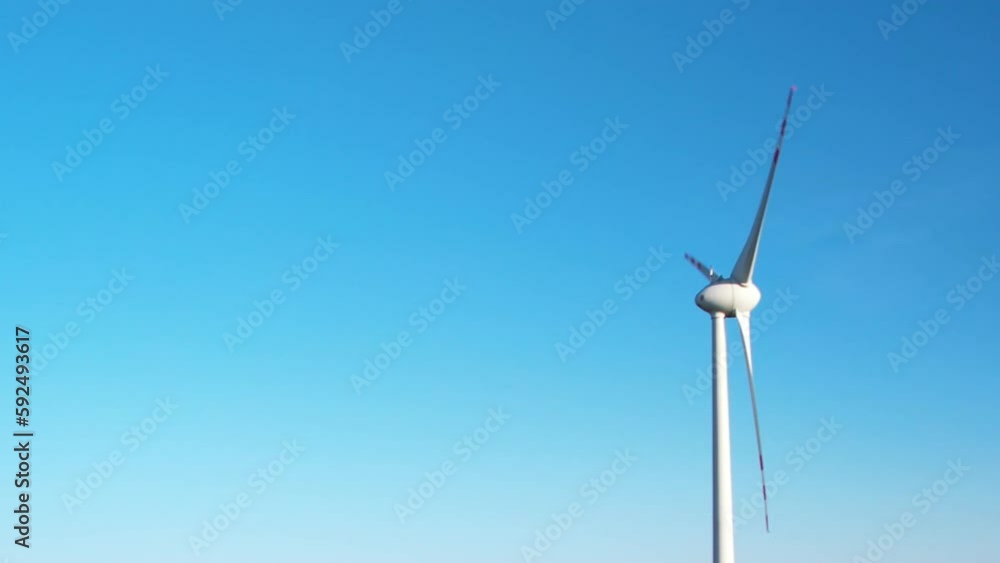 Spinning Blades of Single Wind Turbine Against Blue Sky With Text Space Spinning Blades of Single Wind Turbine Against Blue Sky With Text Space
