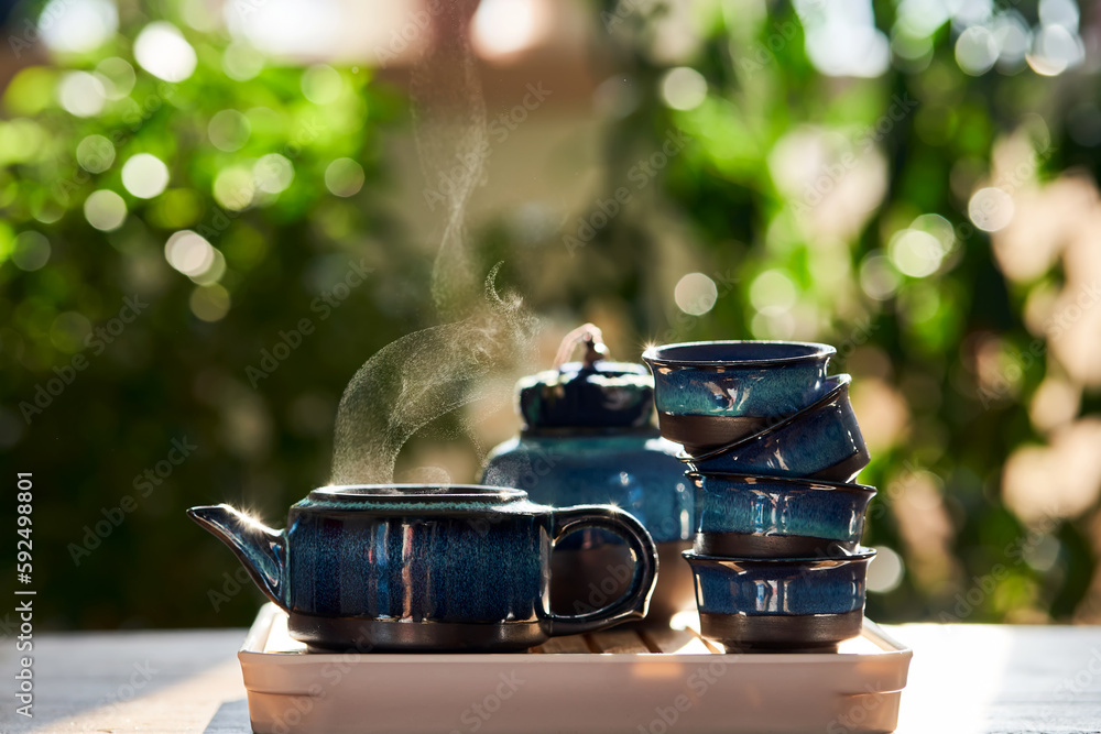 Tea set of deep blue color on a background of greenery.